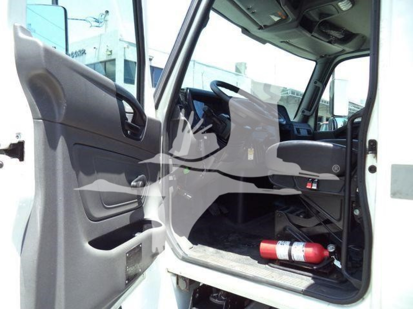 Interior of a 2020 International MV rolloff truck cab showing open driver door, steering wheel, dashboard, and a red fire extinguisher on the floor.