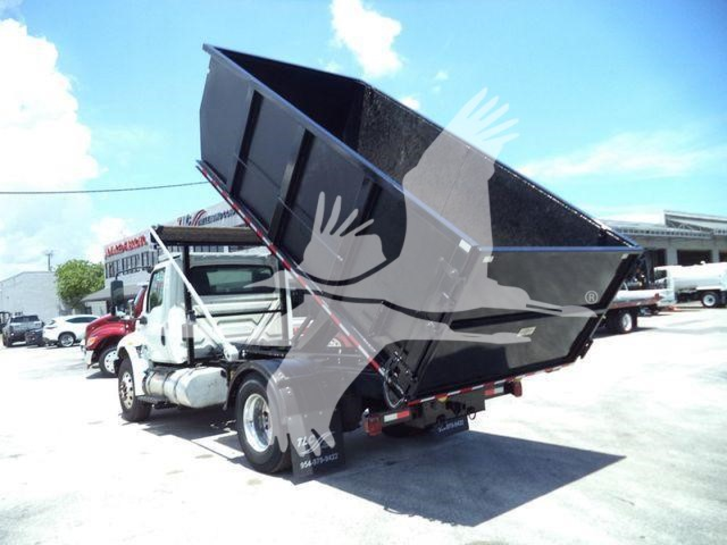 Dump truck in service with raised dump bed showing cargo area and hitch, International MV model, used vehicle.