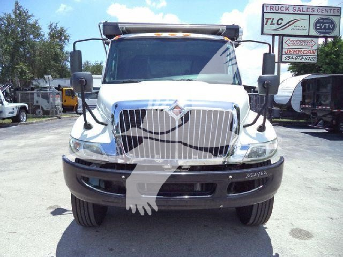 Front view of a white 2020 International MV roll-off truck showing grille, bumper, and large side mirrors.