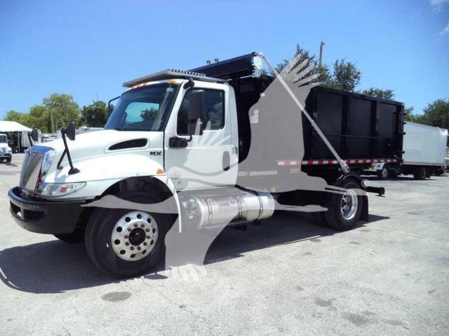 International MV roll-off truck in-service showing cab and open-bed with hydraulic system and front fender details.