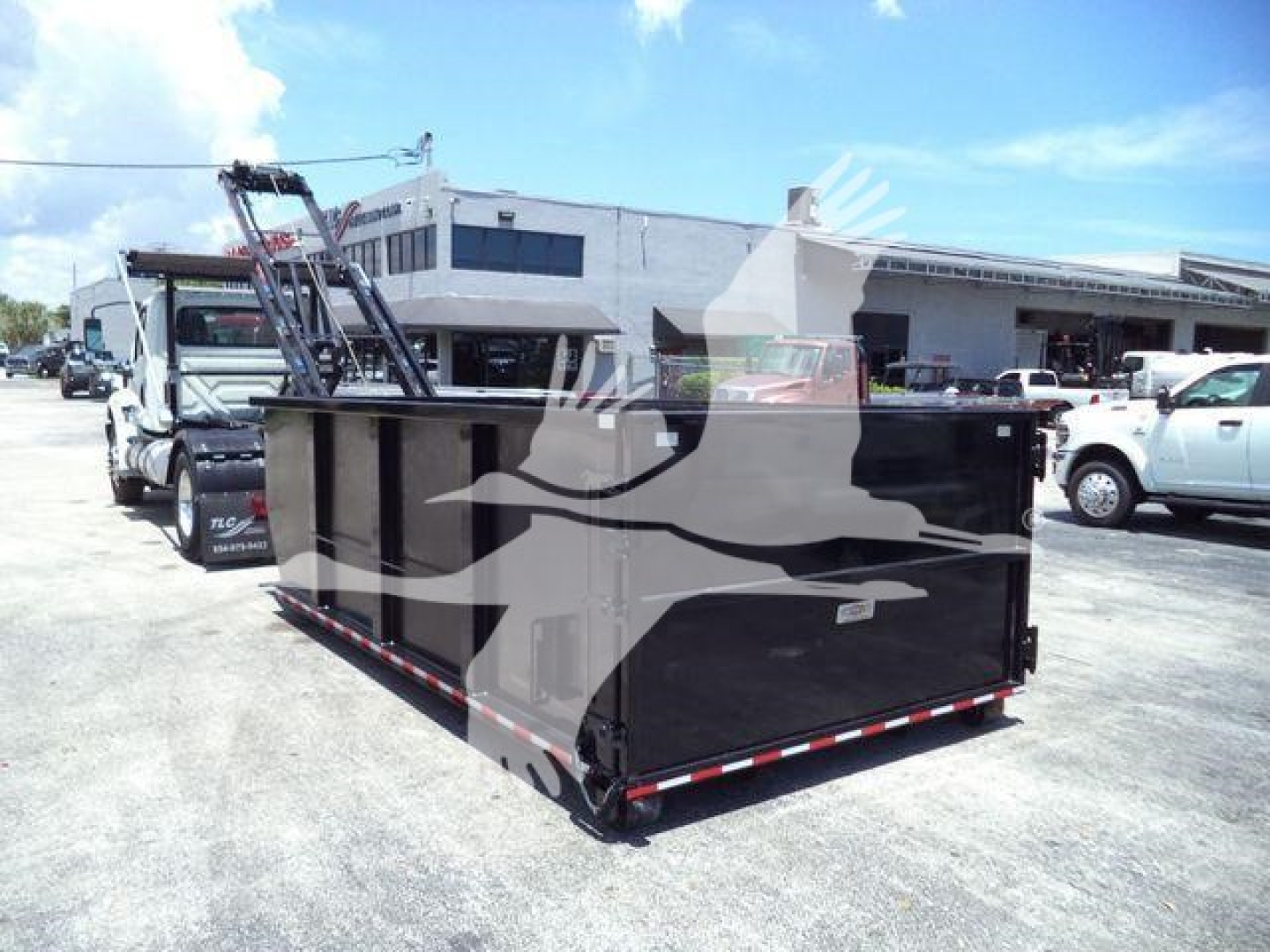 Rolloff truck in yard with large black dumpster attached to a heavy-duty truck; logo watermark across image.