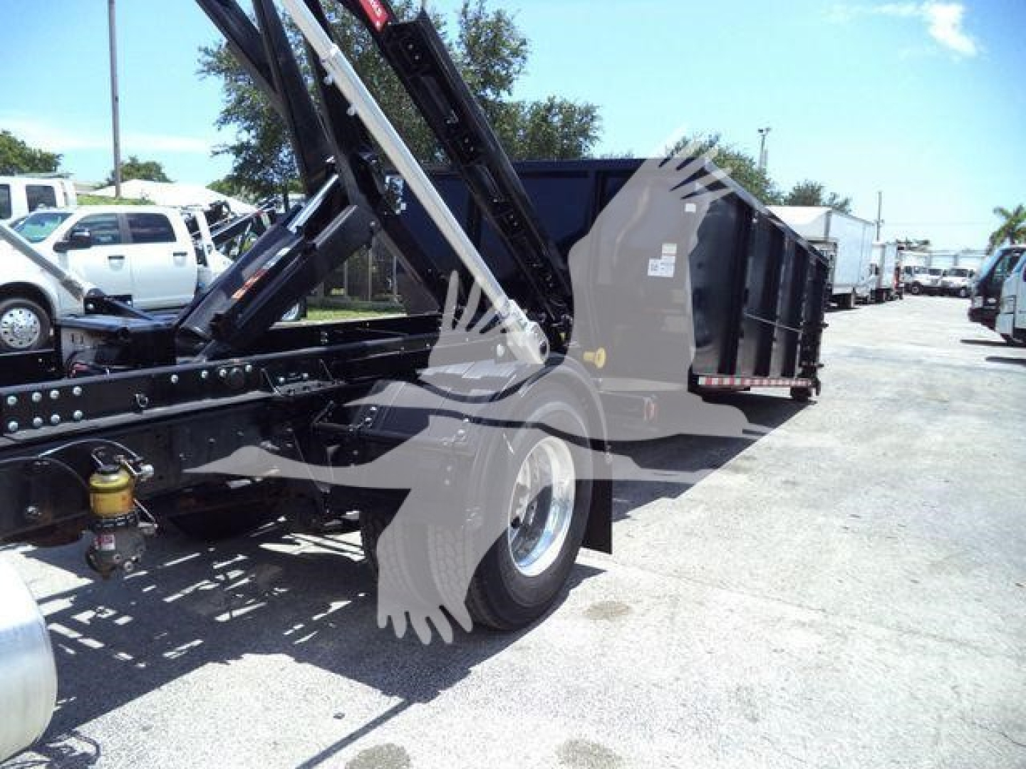Truck bed and hydraulic roll-off arm of a 2020 International MV roll-off truck showing side view and rear wheel
