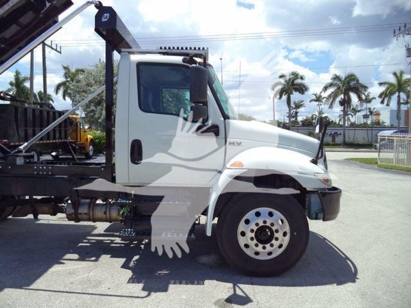 Truck cab of a 2020 International MV rolloff truck shown in side profile with chassis and hook arm visible.