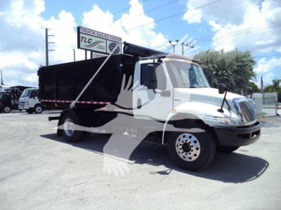 D13-style roll-off truck in a lot showing cab and black dump body; no visible legible labels or part numbers readable on the image.