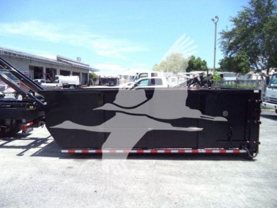 Rolloff truck body in a used 2020 International MV listing showing a large black steel container with reflective red/white stripes and side doors.