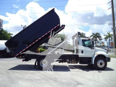 Dump truck with raised bed in service view showing cab and hydraulic dump mechanism.