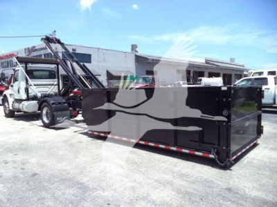 2020 International MV roll-off truck with large black dumpster container attached to truck, side view showing hydraulic crane and long bed.