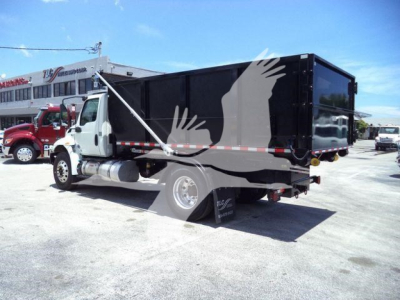 Truck side view showing a black dump body with white cab and chrome fuel tank, International MV 2020 roll-off truck.