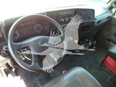 Dashboard and steering wheel of a used 2020 International MV roll-off truck interior showing steering wheel, instrument cluster, center console, and pedals.