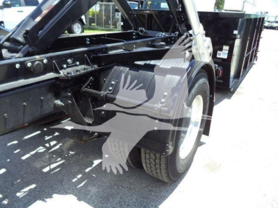 Tow truck chassis and front wheel assembly showing hydraulic components and roll-off bed in service condition.