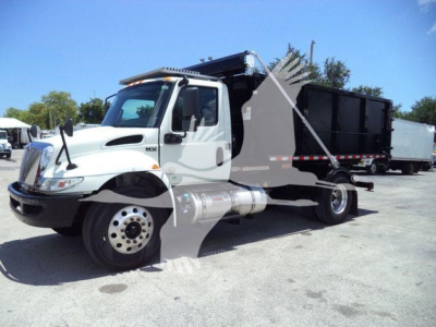 International MV roll-off truck in-service showing cab and open-bed with hydraulic system and front fender details.