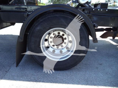 Wheel well and front tire of a 2020 International MV roll-off truck showing wheel and fender components.