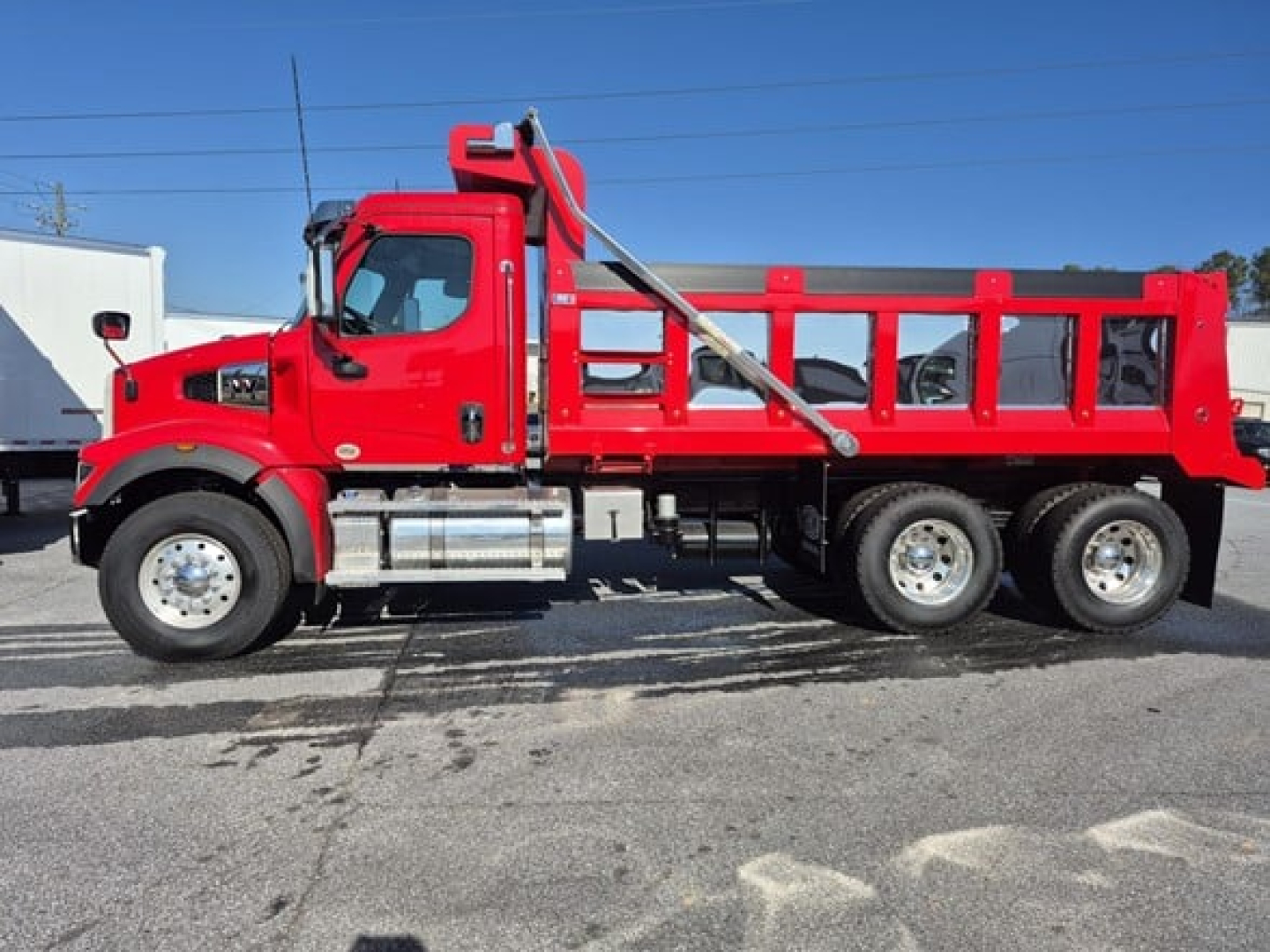 Western Star 47x dump truck side view showing red cab and dump body with dual rear axles.