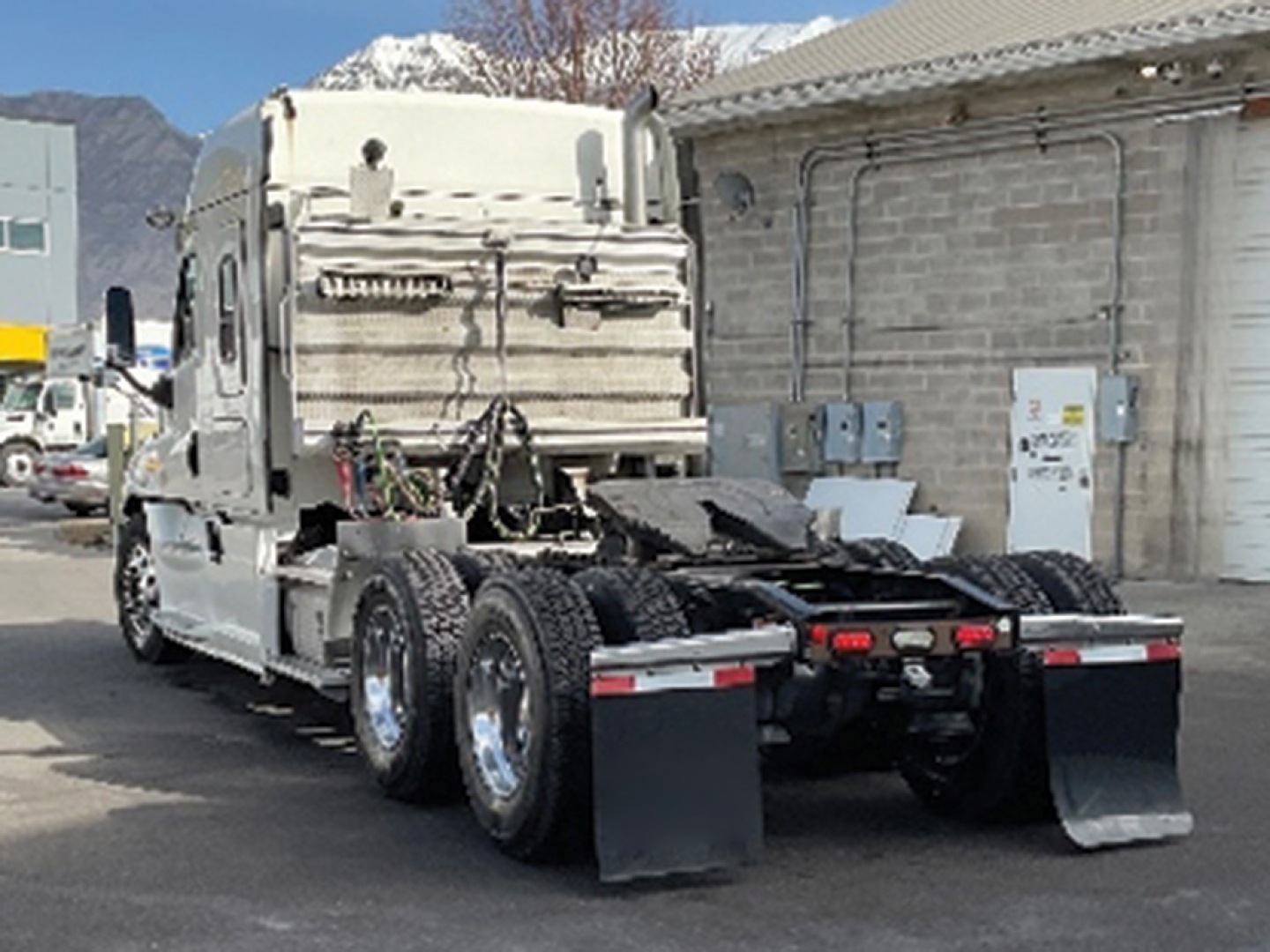 Conventional sleeper Freightliner Cascadia125 tractor rear view showing fifth wheel, dual rear axles, mud flaps, and chassis components.