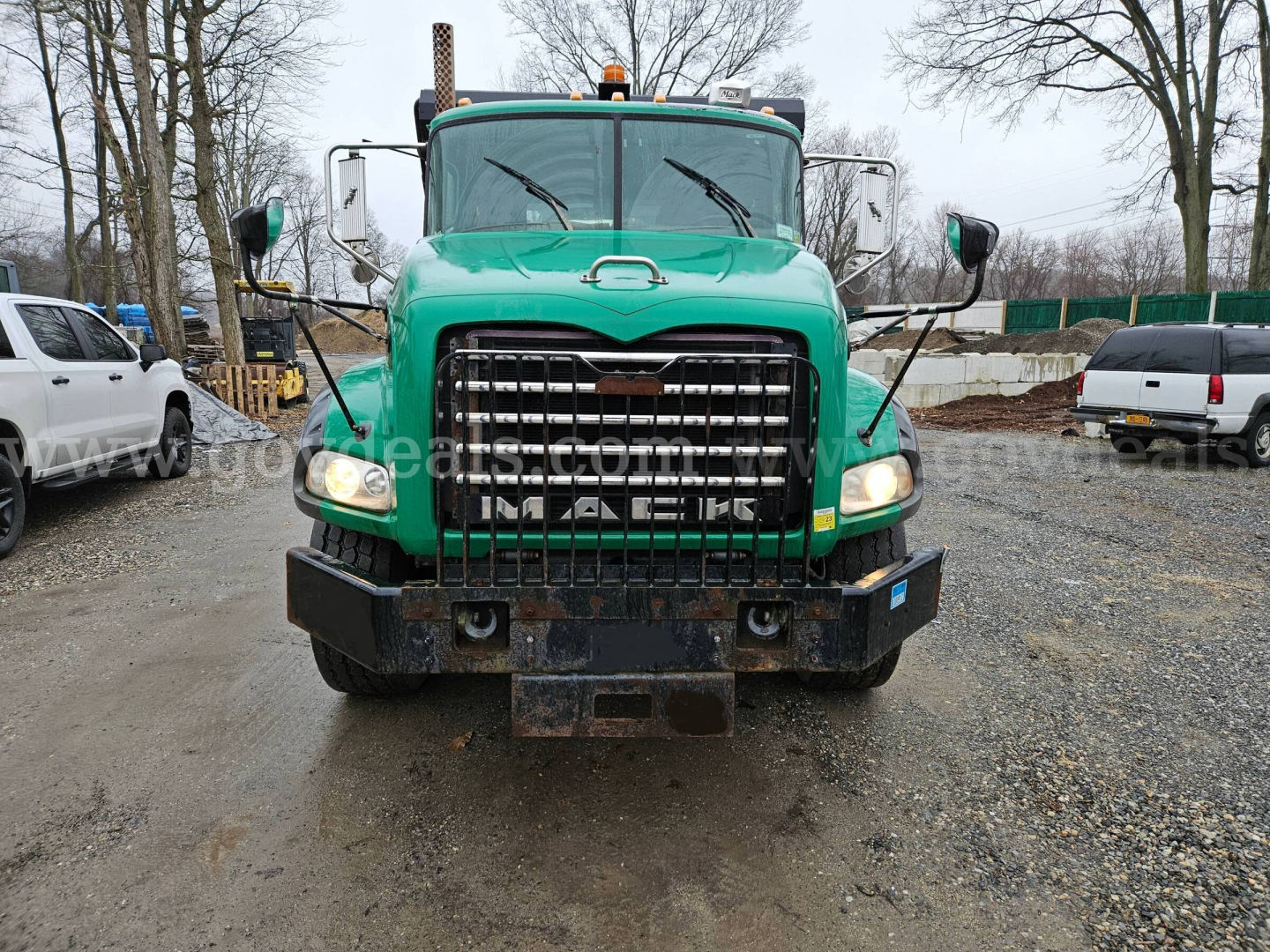 Front view of green 2008 Mack GU813 roll-off truck showing large grille, bumper, and headlights.