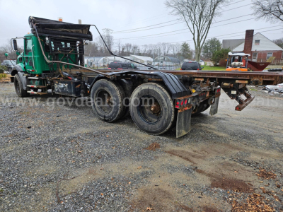 Tractor unit with flatbed trailer chassis in service showing rear triple axle and Mack GU813 identification.