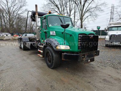 Green 2008 Mack GU813 roll-off truck front-left view showing cab, grille, headlights, and bumper.