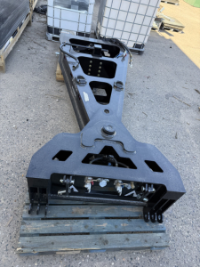 Trailers: 55 ton 8'-6'' Alpha Spreader Bar front view showing attachment pins and hydraulic manifolds on a lowboy trailer component.