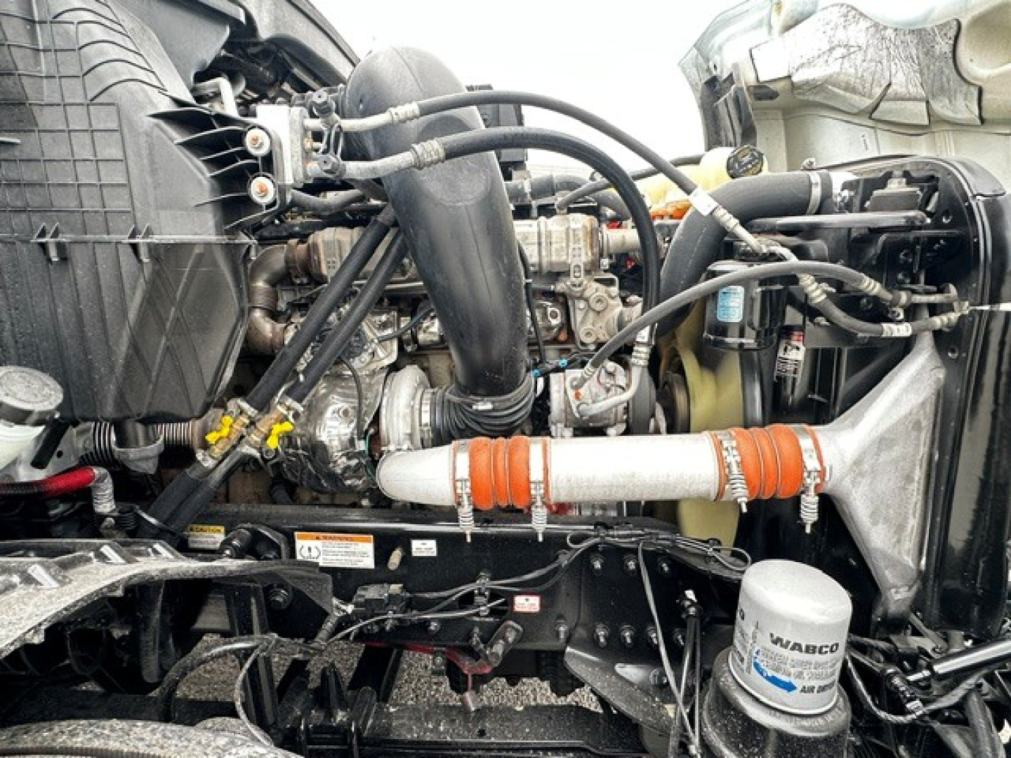 Freightliner Cascadia 126 engine bay showing turbocharger, hoses, radiator, air intake, coolant reservoir, filter canister, and intercooler pipes.