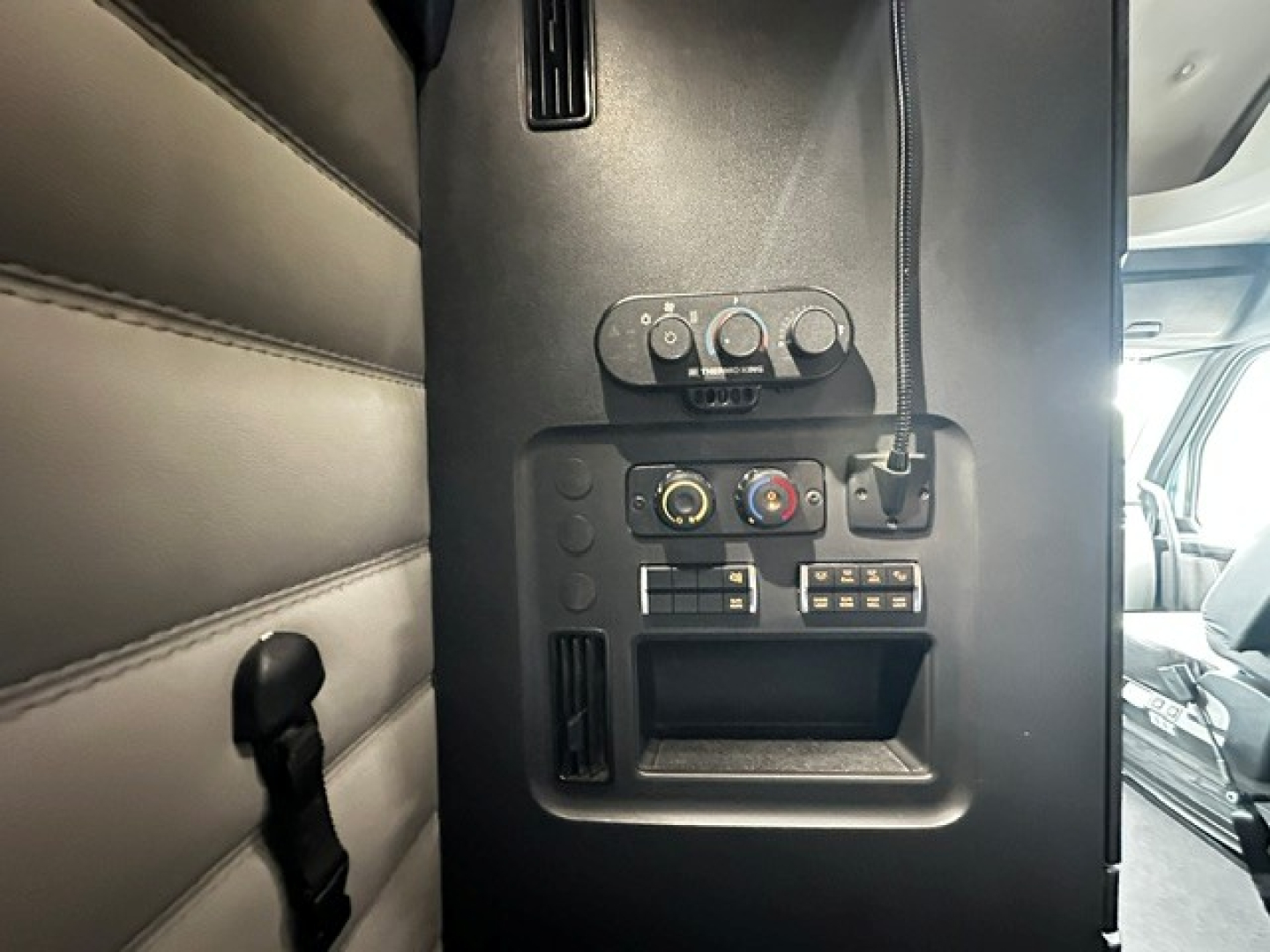 Freightliner Cascadia 126 interior panel showing climate controls and 12V/USB outlets and storage pocket.