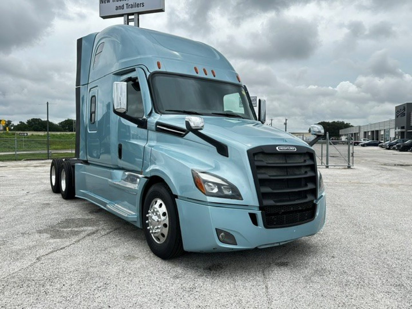 Freightliner Cascadia 126 tractor profile in blue, front-left view, with black grille and dual wheels, daytime overcast sky.