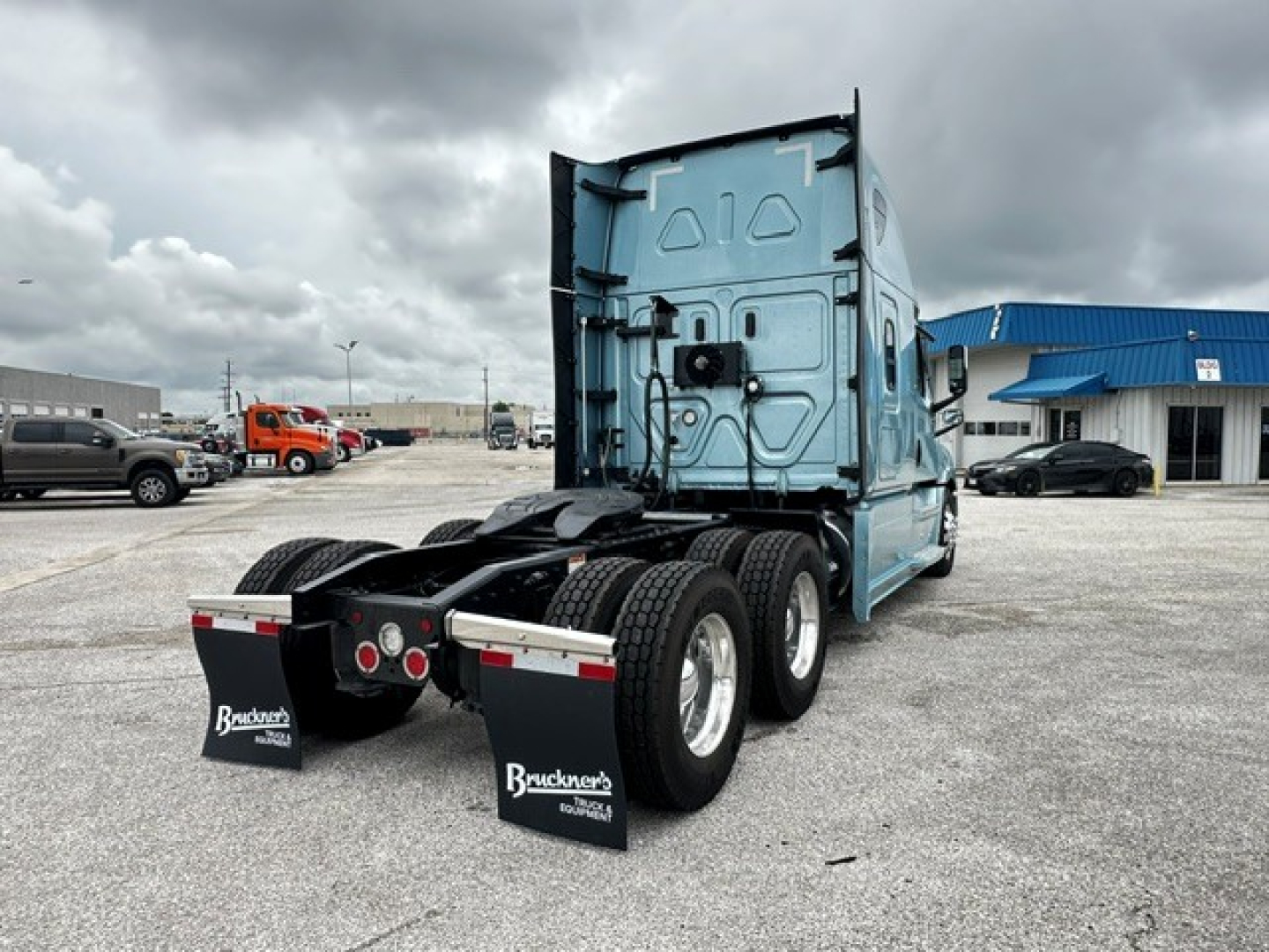 Freightliner Cascadia 126 tractor rear view showing sleeper cab, dual rear wheels, mud flaps, and chassis in a truck lot.