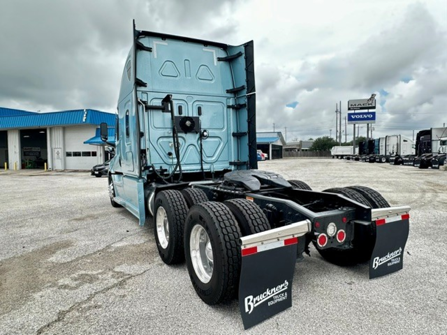 Truck rear view showing Freightliner Cascadia 126 sleeper chassis with dual rear axles and blue cab.