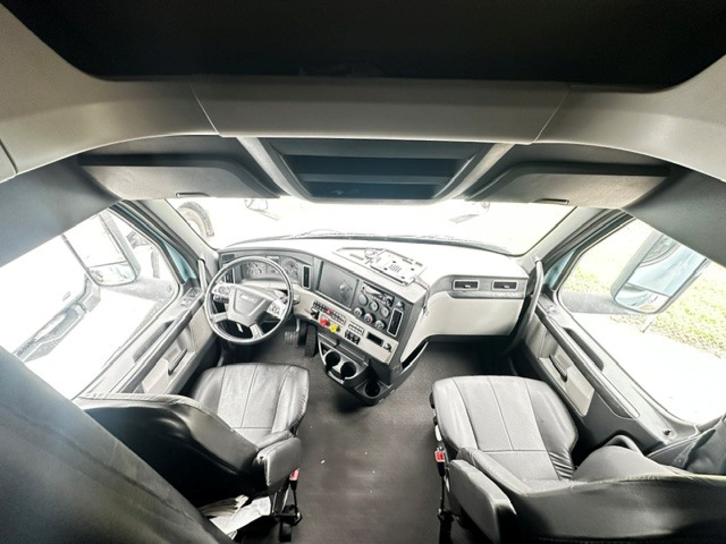 Intricate view of Freightliner Cascadia 126 cab interior with steering wheel, dashboard, and two seats; no legible text visible on components.