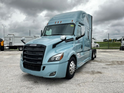 2023 Freightliner Cascadia 126 tractor cab front-right view showing blue exterior, large grille, dual mirrors, and sleeper cab with aerodynamic mirrors.