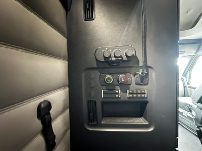 Freightliner Cascadia 126 interior panel showing climate controls and 12V/USB outlets and storage pocket.