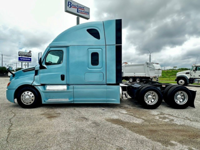 Truck cab side view showing blue Freightliner Cascadia 126 sleeper with enclosed cab and dual rear axles.