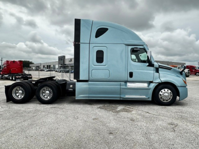 Truck side view of a blue 2023 Freightliner Cascadia 126 tractor with sleeper cab, dual rear axles, and chrome accents.