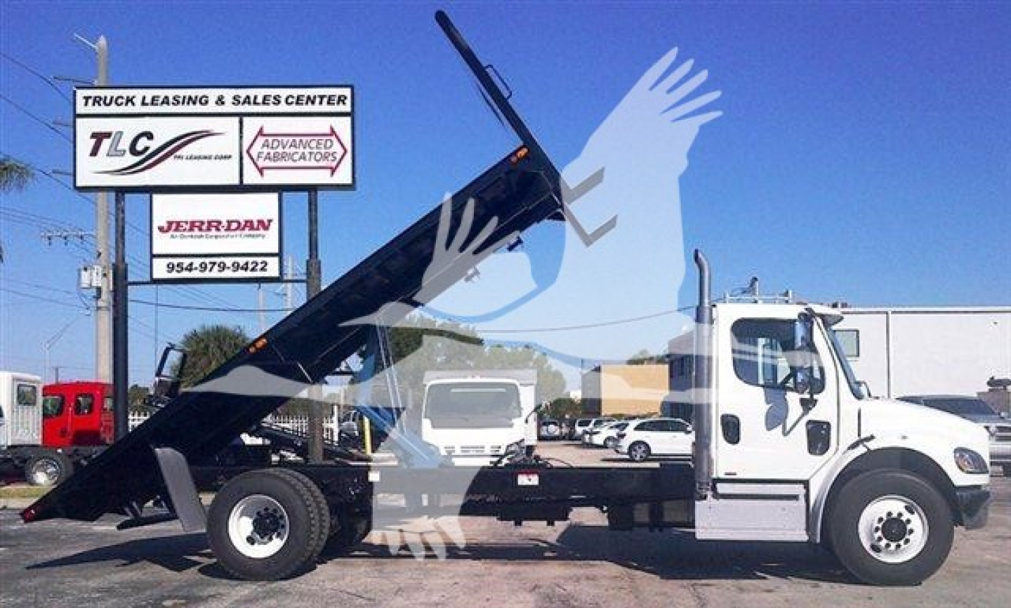 Flatbed tow truck with extended dump body showing 20 ft bed and hydraulic hoist, TLC Advanced Fabricators sign in background.