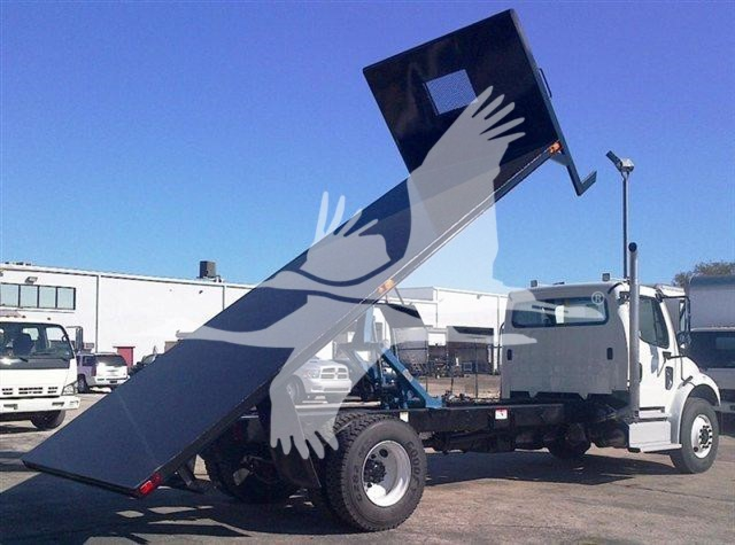 Flatbed truck with a raised dumping bed showing the metal frame and hydraulic mechanism.