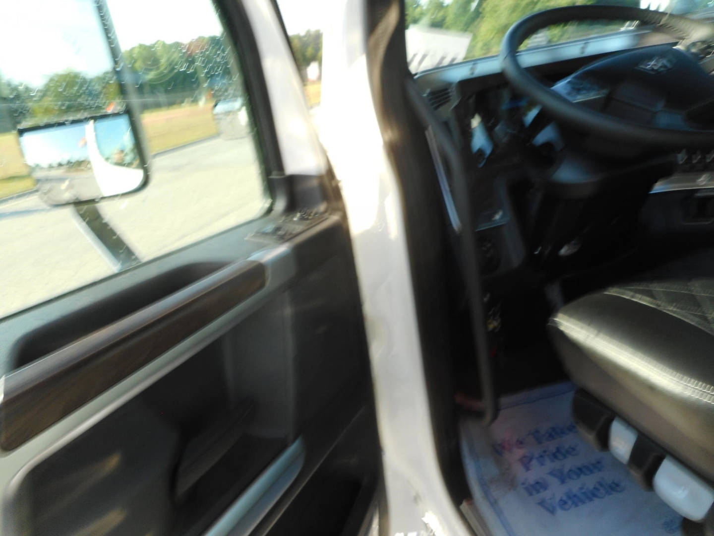 Truck cab interior view showing driver seat and steering wheel from the open door; faint dashboard details visible.