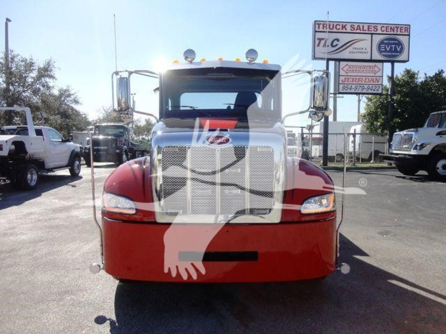 Front view of a 2022 Peterbilt 337 rollback truck showing large chrome grille, red lower bumper, and side mirrors; dealership signage in background.
