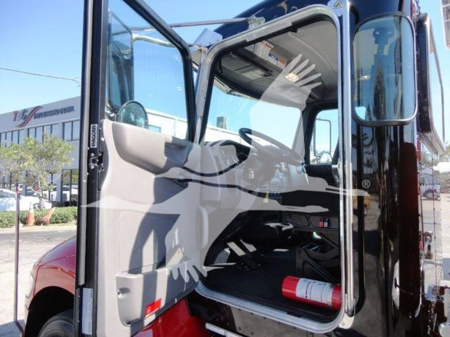 Peterbilt 337 exterior cab view with open door showing interior steering wheel and dashboard, rollout truck front section visible.
