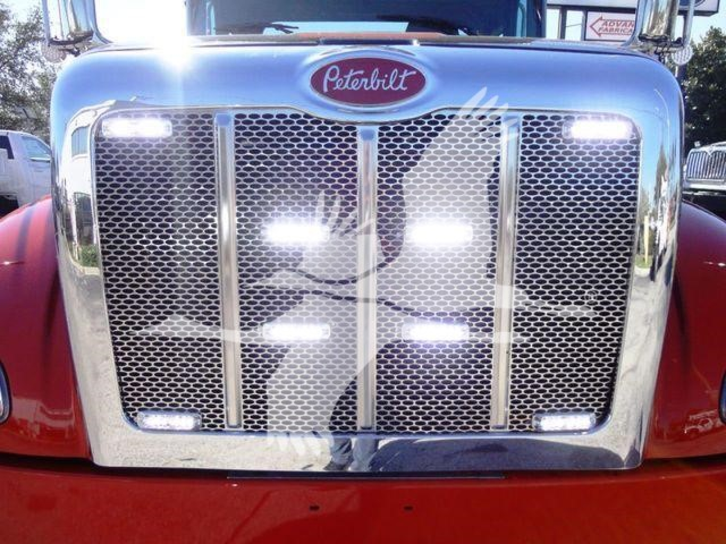 Peterbilt 337 front grille with bright headlights, chrome grille bars, Peterbilt emblem, red cab.