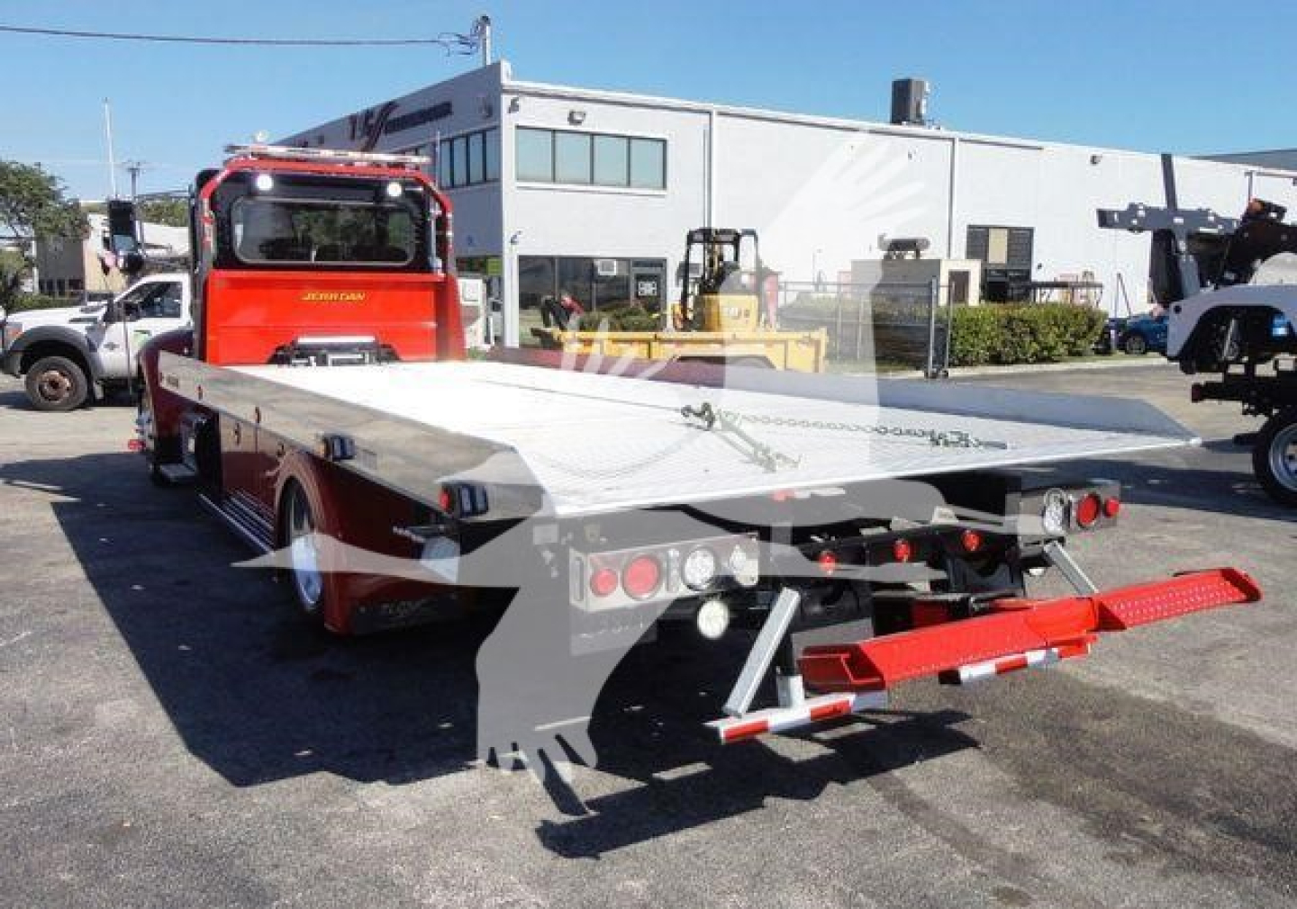 Peterbilt 337 rollback tow truck with flatbed, red cab, gray flatbed, rear lights, and towing equipment visible.