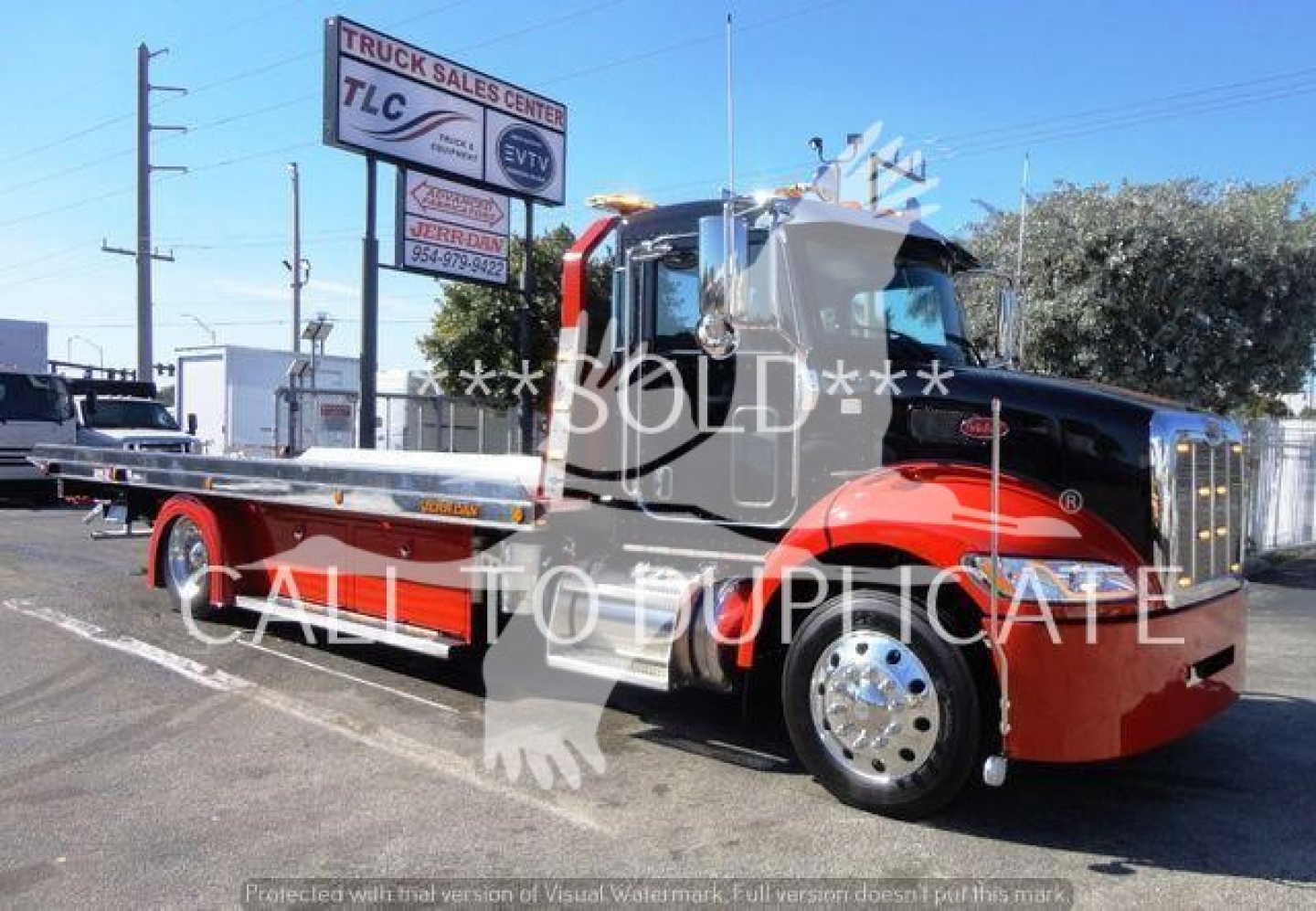 Peterbilt 337 rollback tow truck in red and black color showing long flatbed and chrome wheels.