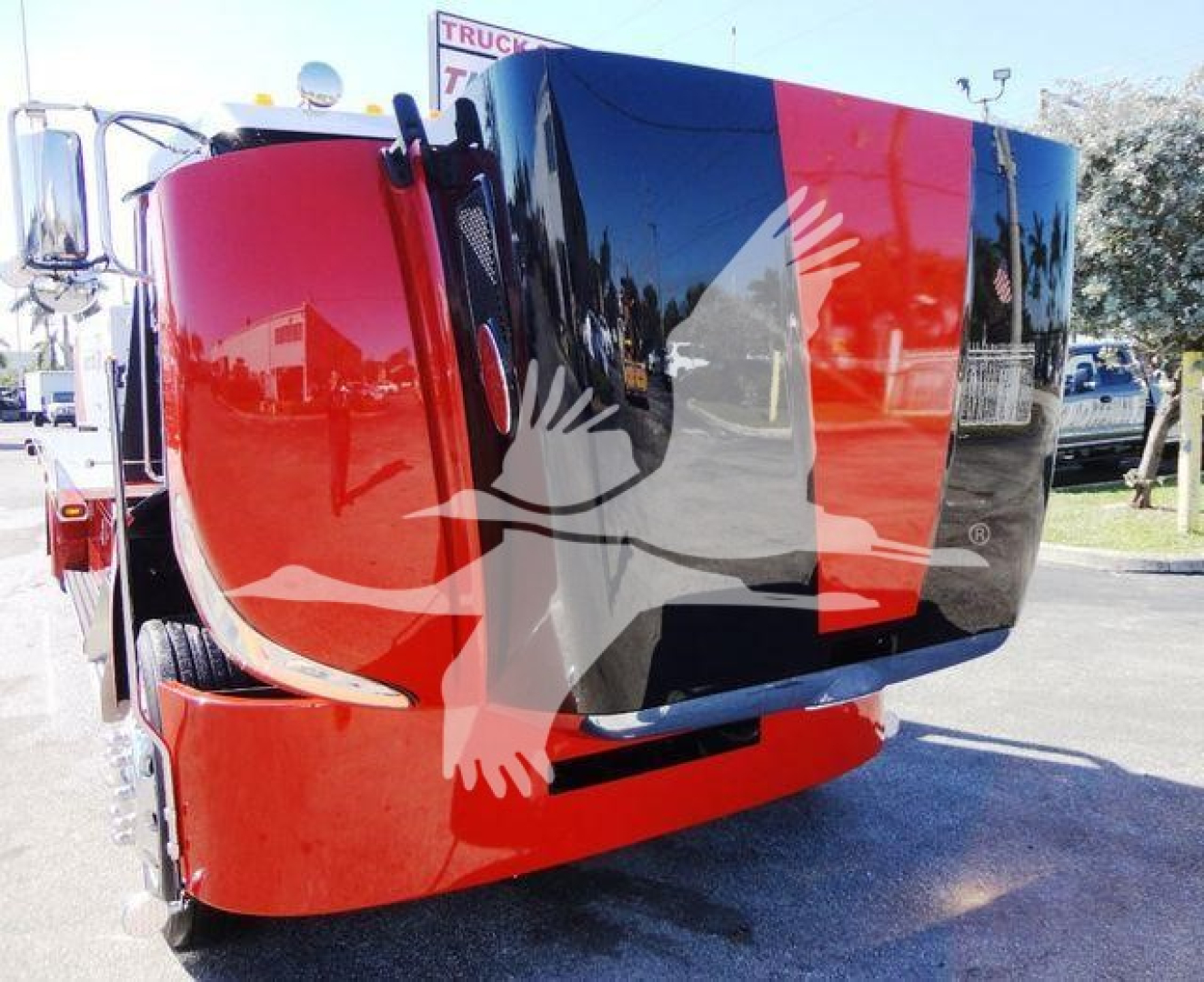 Peterbilt 337 rollback truck showing bold red and black paint scheme with cab tilted forward, windshield reflections, and side mirror.
