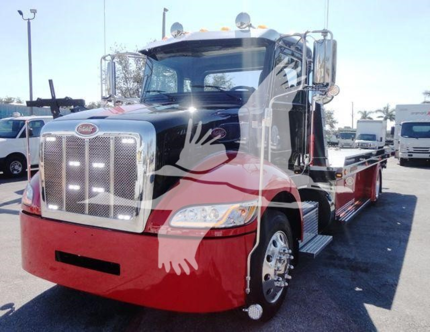 Peterbilt 337 rollback truck front-left view showing chrome grille, dual mirrors, red lower bumper, and black cab with chrome steps.