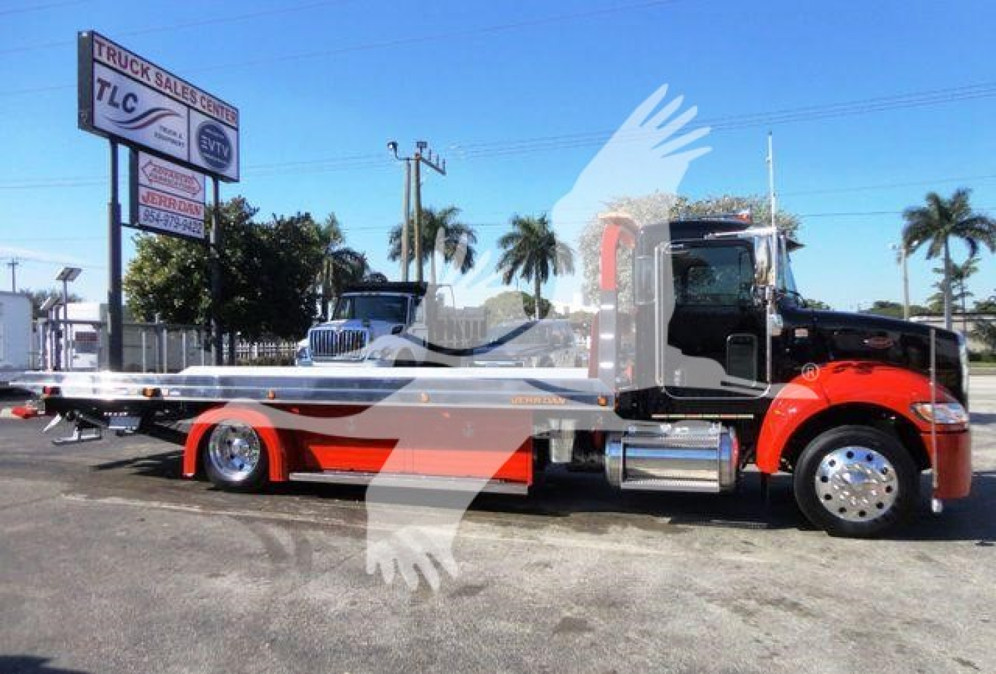 Peterbilt 337 rollback truck side view with red and black cab and flatbed, dealership lot background