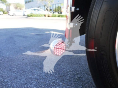 Truck wheel and hitch area of a 2022 Peterbilt 337 rollback truck showing a pink-lidded filter or cap near the wheel.