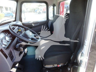 Truck cab interior showing steering wheel, dashboard, driver and passenger seats, window view.