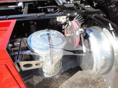Peterbilt 337 rollback truck component showing air hose reel and cylindrical fluid reservoir with clear cap.