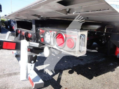 Rear of a Peterbilt 337 rollback truck showing taillights, bumper, and hydraulic equipment under a raised bed, with reflectors and brackets.