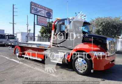 Peterbilt 337 rollback tow truck in red and black color showing long flatbed and chrome wheels.