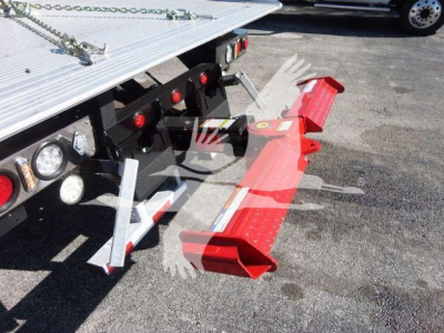 Peterbilt 337 rollback truck rear with red tongue and hydraulic lift components visible, reflective lights, platform, and safety chains.