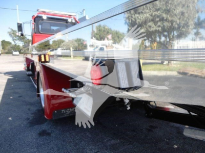 Peterbilt 337 rollback truck with reflective chrome side railing and red cab, rear view showing wheel and platform.